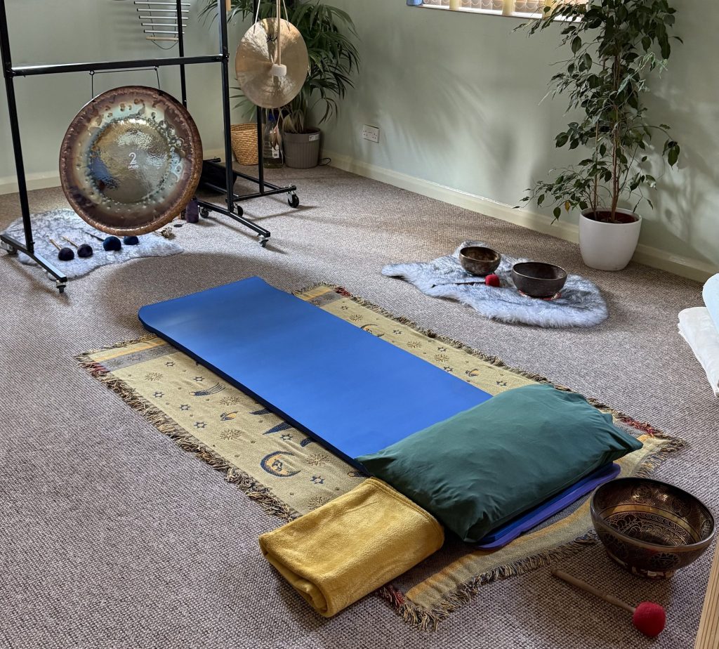 Welcoming sound therapy room with gong, singing bowls, mat and cushions.